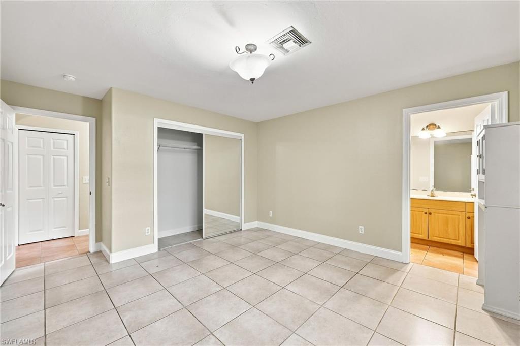 Spacious kitchen featuring tile flooring, ample cabinet storage, built-in refrigerator, and multiple entry points
