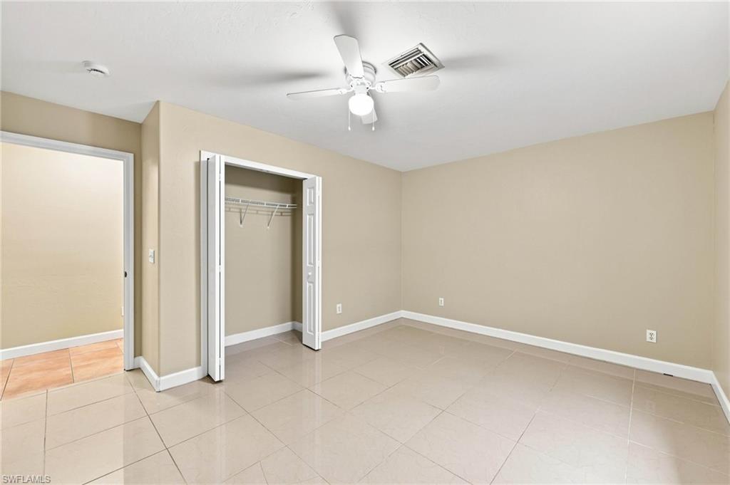 Spacious room featuring neutral tone walls, large format tile flooring, and a ceiling fan with integrated lighting