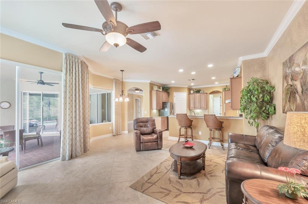 Spacious living area featuring tile flooring, crown molding, a ceiling fan, and access to a screened patio