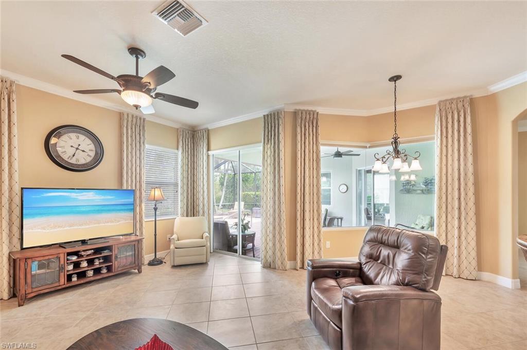 Spacious living area featuring neutral wall tones, crown molding, and tile flooring