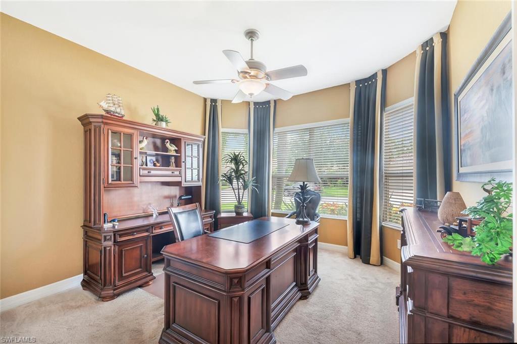Carpeted room with a ceiling fan light fixture and multiple windows featuring blinds and curtains