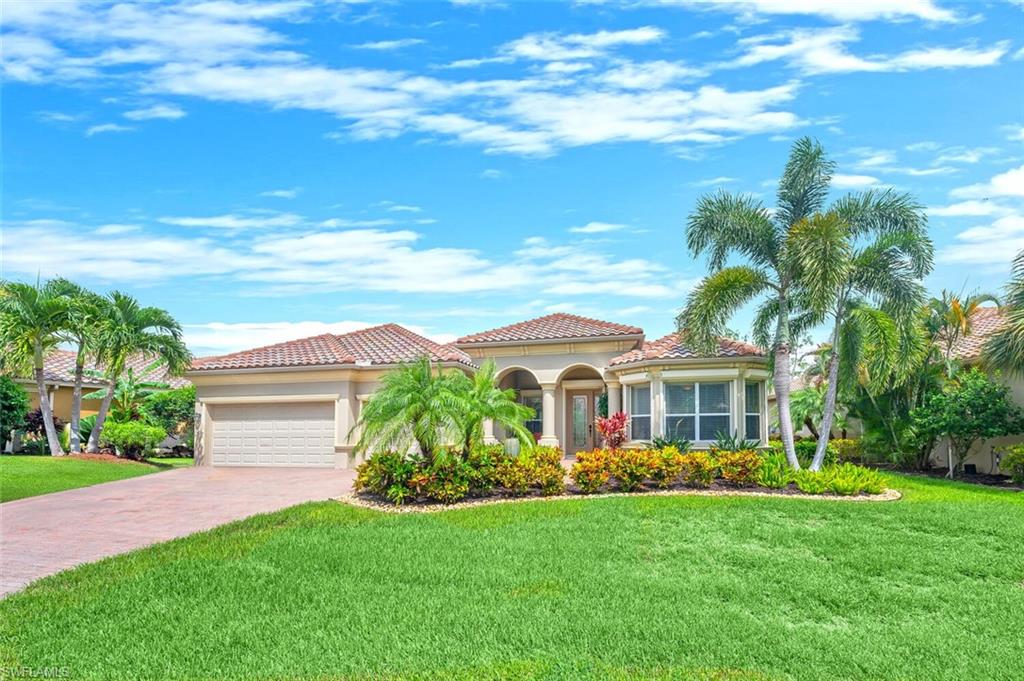 Mediterranean-inspired residence featuring a tile roof, an integrated garage, and a paver driveway