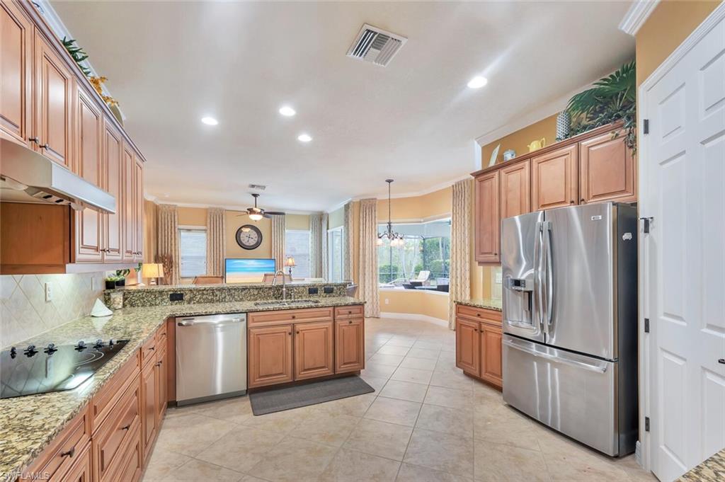 Kitchen featuring wood cabinetry, granite countertops, stainless steel appliances, and tile flooring