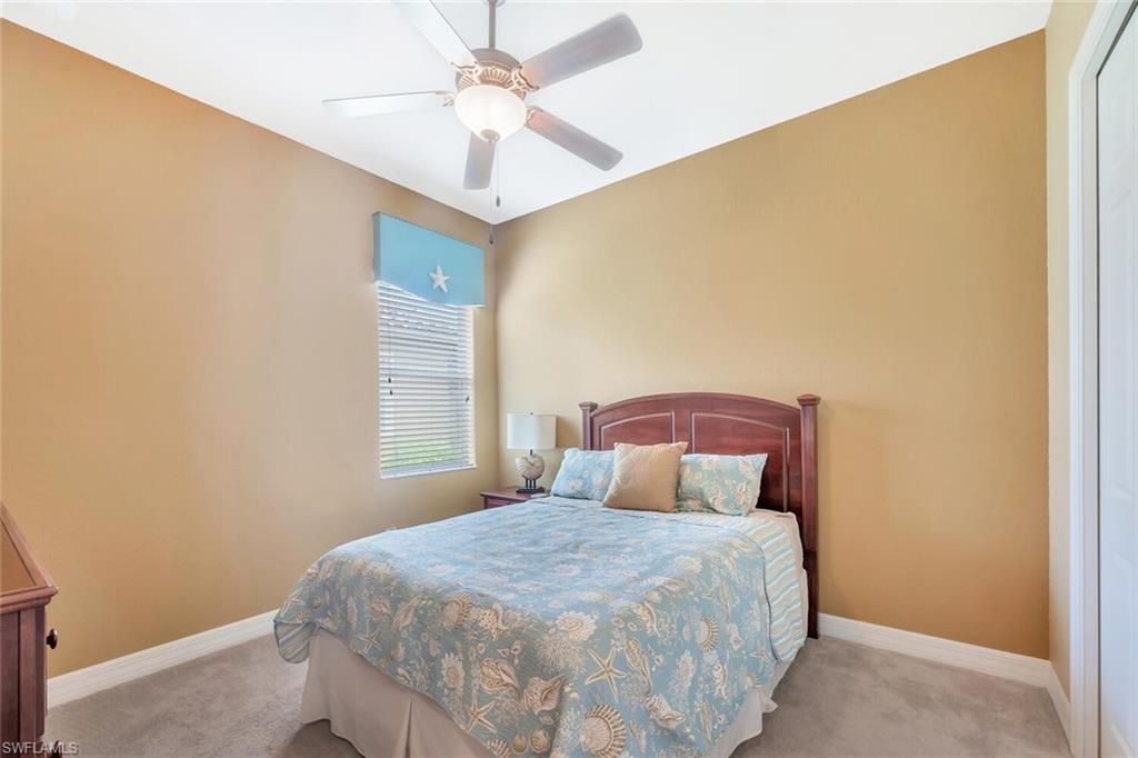 Carpeted room featuring a ceiling fan with integrated lighting, a window with horizontal blinds, and a solid white door