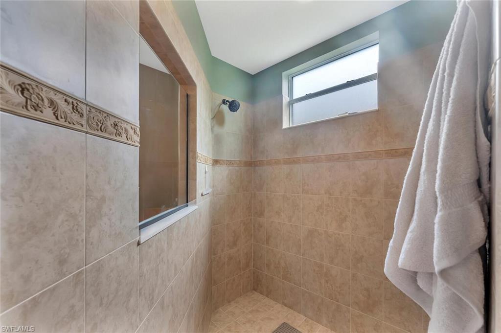 Spa-inspired master bath featuring a spacious walk-in shower with frameless glass enclosure, dual showerheads, and tumbled stone tile surround