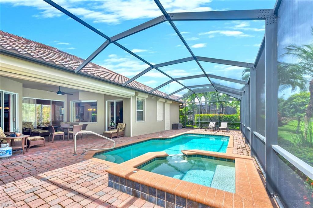 Screened lanai featuring a swimming pool, integrated spa, and extensive brick paver patio
