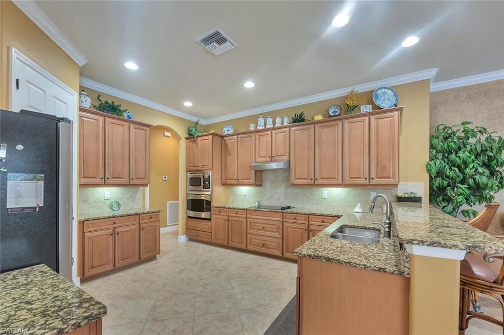 Spacious kitchen featuring extensive wood cabinetry, granite countertops, tile flooring, and recessed lighting