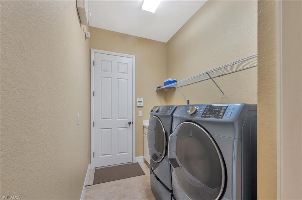 Dedicated laundry space featuring a white paneled door, light-toned walls, and a built-in wire shelving unit
