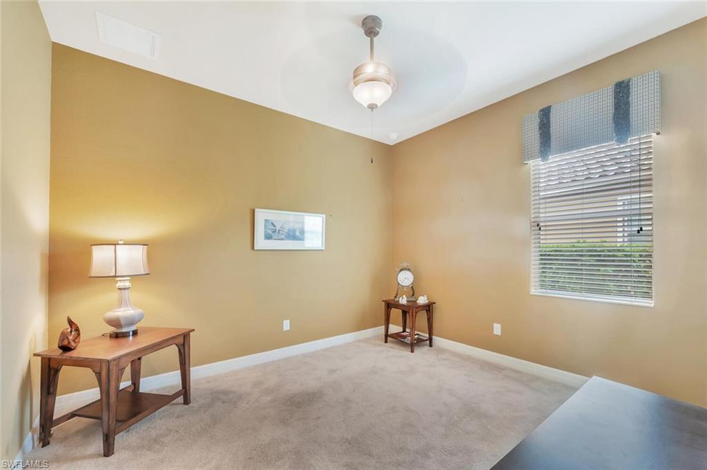 Carpeted room featuring a ceiling fan with integrated lighting, a window with horizontal blinds, and warm-toned wall paint