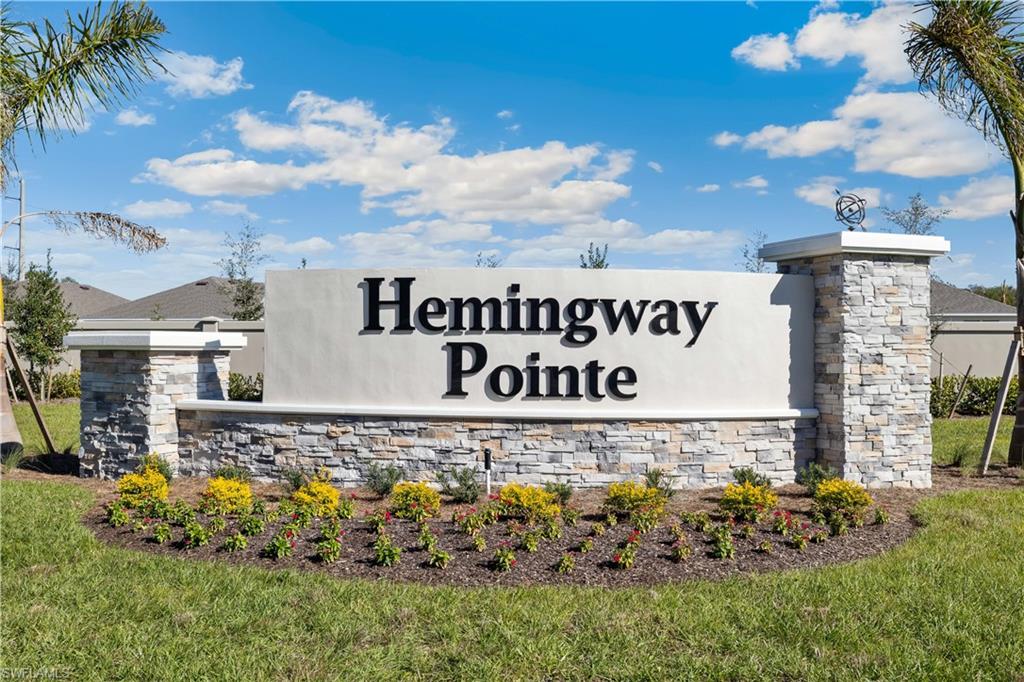Stone-clad community entrance sign with raised lettering, accented by a decorative finial
