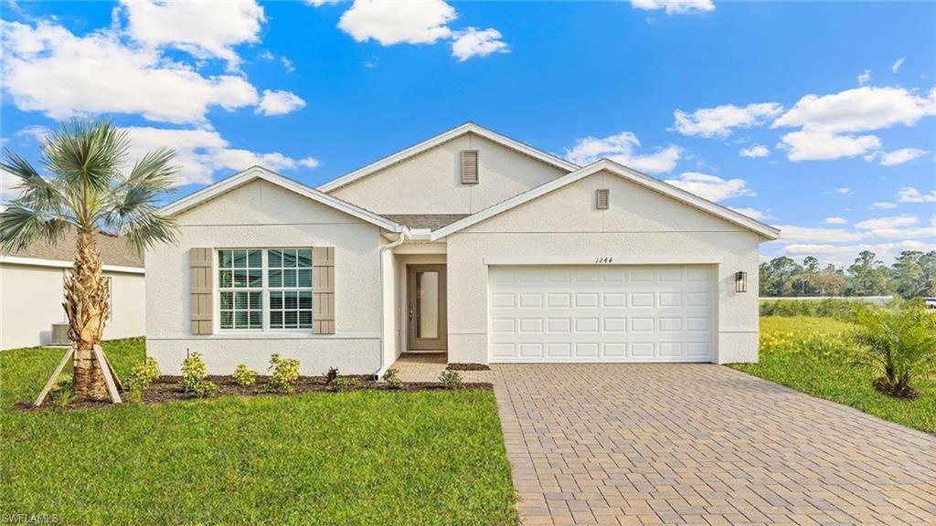 Model Home. Contemporary exterior featuring stucco siding, a gabled roofline, a two-car garage, and a paver driveway