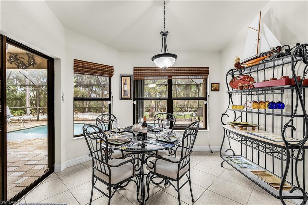 Dining area featuring tile flooring, multiple windows with natural wood blinds, and direct access to the outdoor patio and pool area
