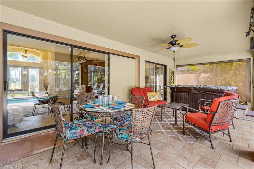 Covered patio featuring a ceiling fan, tile flooring, and a hot tub