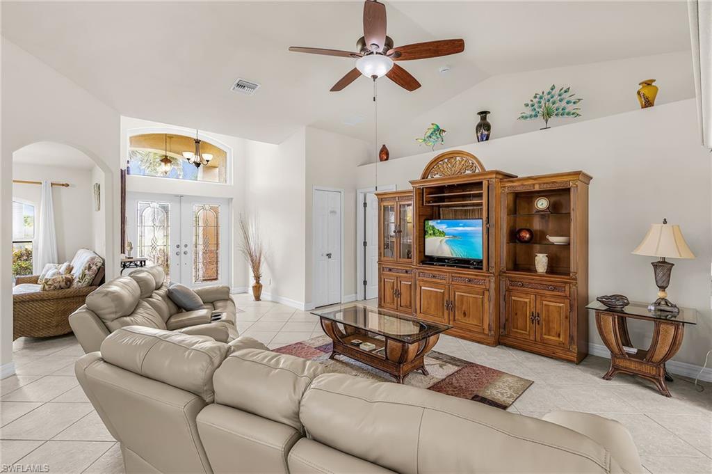 Spacious living area featuring vaulted ceilings, neutral tile flooring, and a built-in entertainment center