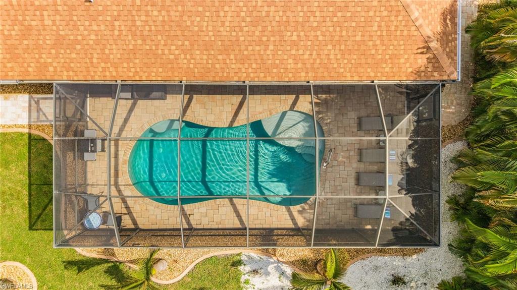 Screened enclosure featuring a freeform swimming pool and paver patio