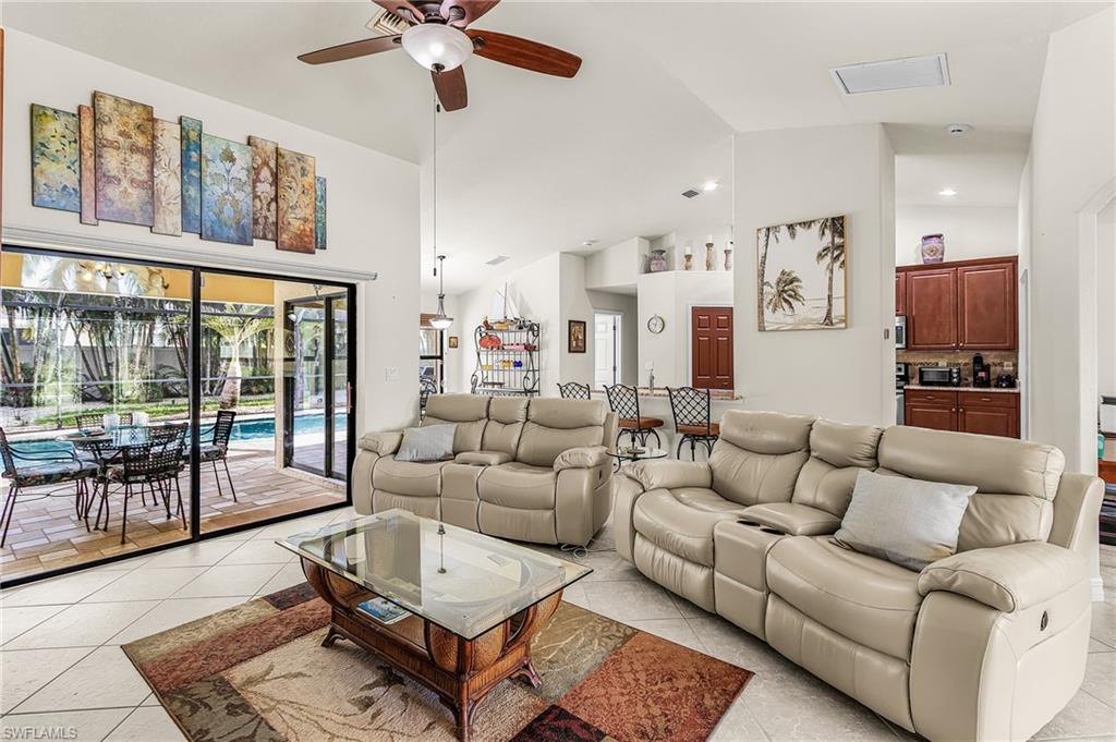 Spacious living area featuring neutral tile flooring and vaulted ceilings
