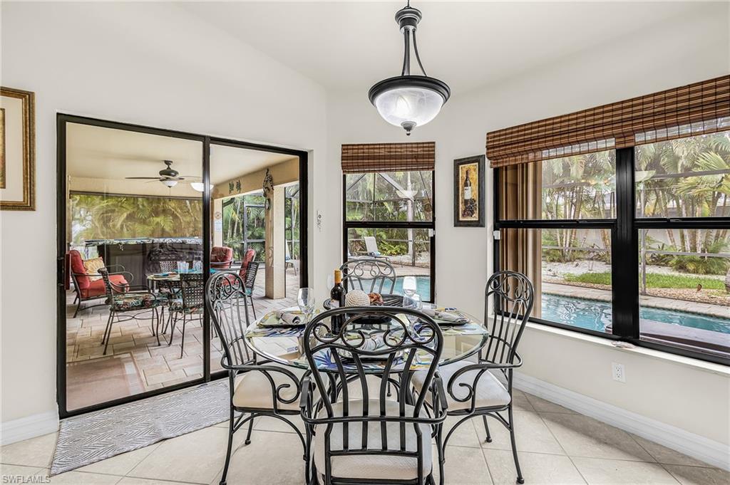 Interior dining area featuring ceramic tile flooring, a glass-top table, and a pendant light fixture