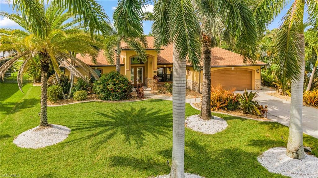 Lush tropical landscaping surrounds this stucco exterior home with a two-car garage