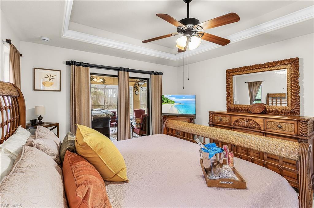 Tray ceiling with crown molding, wood-finish ceiling fan with integrated lighting, and direct access to the outdoor screened enclosure through double sliding glass doors