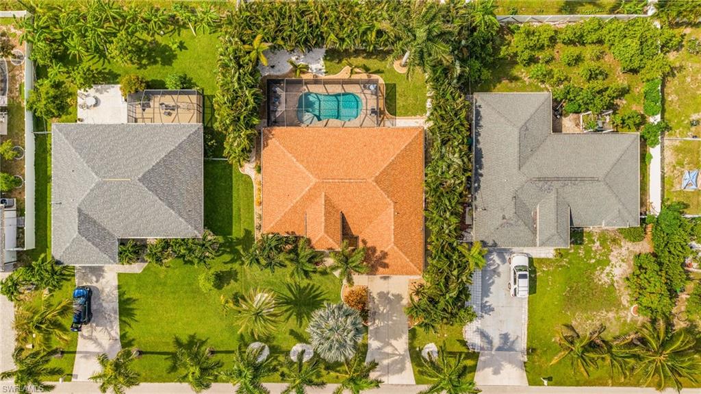 Property featuring a terracotta tile roof, a swimming pool, and a well-maintained lawn with mature palm trees