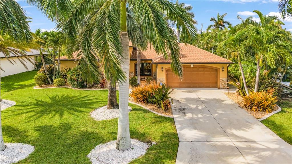 Tropical-inspired exterior featuring a tan stucco finish and a brown tile roof