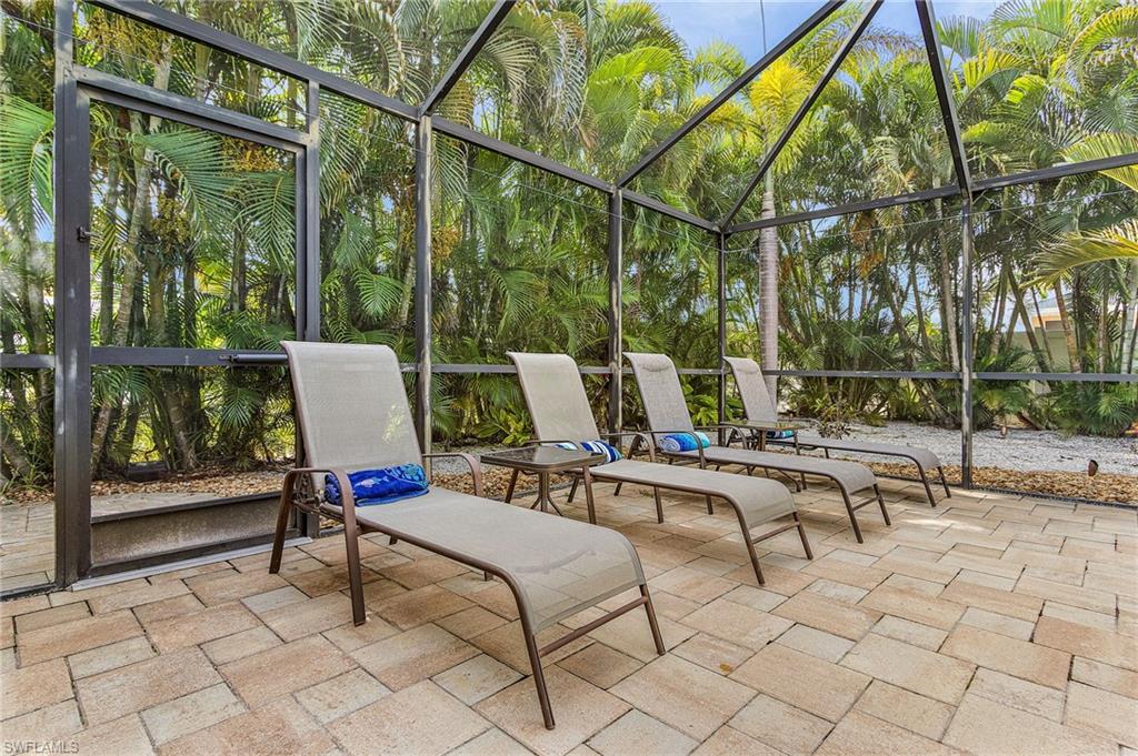 Covered lanai with metal frame structure and polycarbonate roof panels, furnished with loungers and side tables