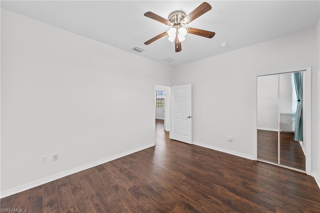 Unfurnished bedroom featuring a closet, dark wood-style flooring, and a ceiling fan