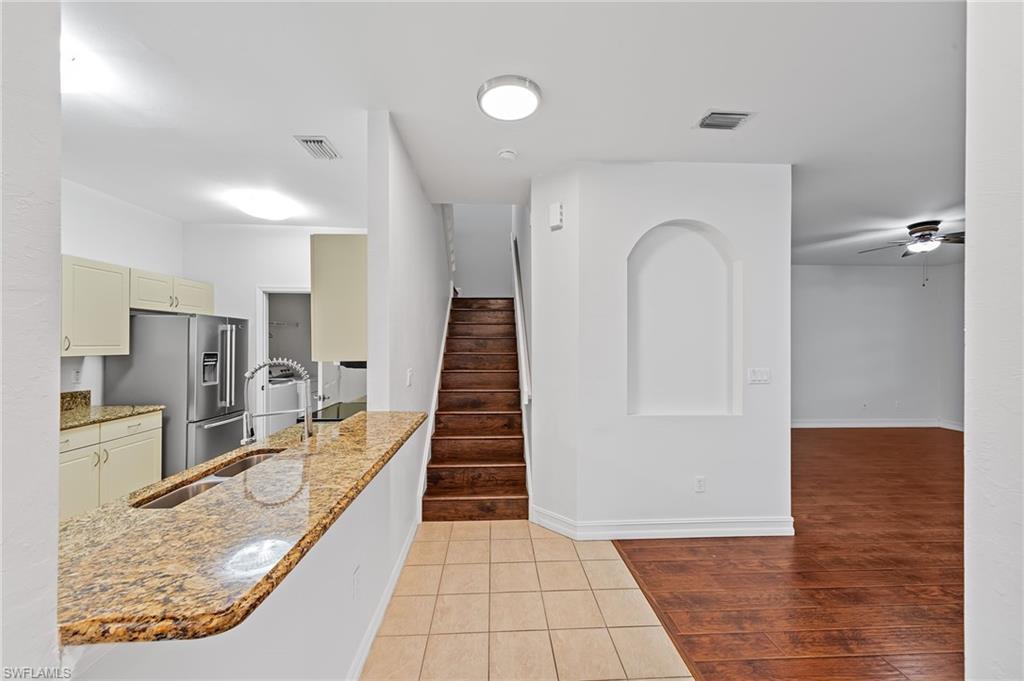 Kitchen with light stone counters, a ceiling fan, light tile patterned flooring, high end fridge, and cream cabinetry