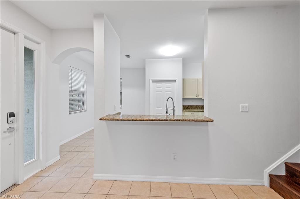 Kitchen with light stone counters, arched walkways, and light tile patterned floors