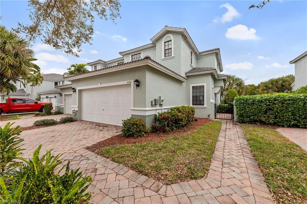 Mediterranean / spanish home featuring a gate, stucco siding, decorative driveway, a tiled roof, and a garage