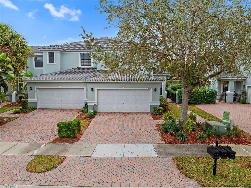 View of front of house with stucco siding, decorative driveway, a garage, and a tiled roof
