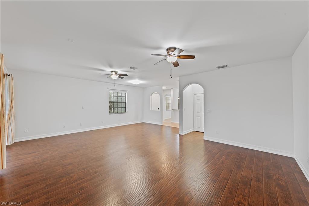 Spare room featuring arched walkways, dark wood finished floors, and a ceiling fan