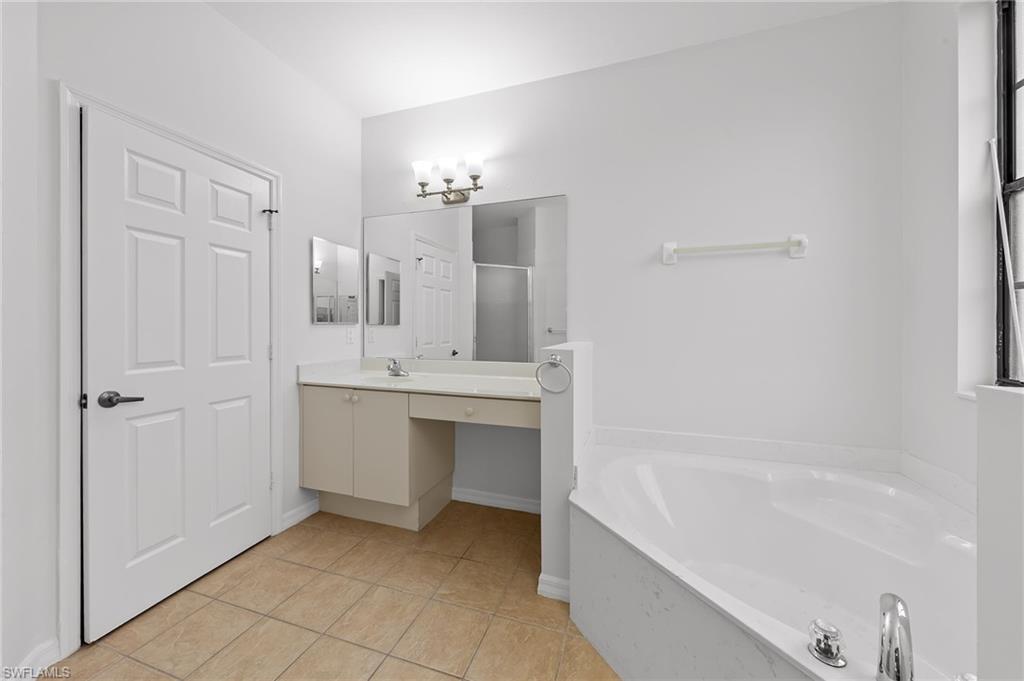 Bathroom featuring vanity, a stall shower, a bath, and light tile patterned floors
