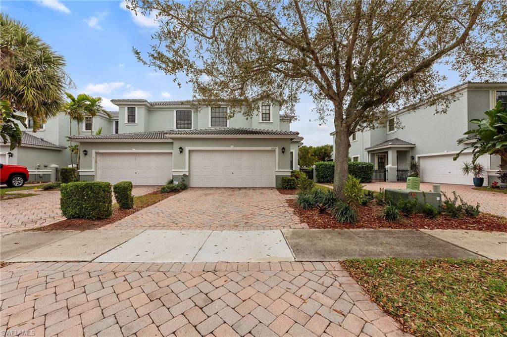 View of front facade featuring decorative driveway, stucco siding, an attached garage, and a tile roof