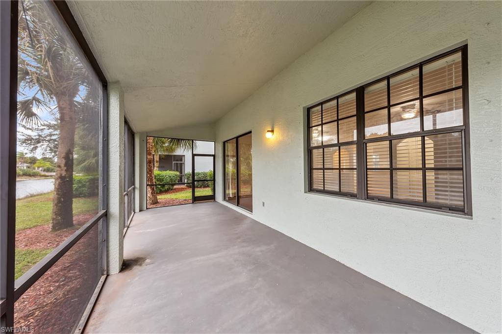 Unfurnished sunroom featuring concrete floors, a textured wall, and lofted ceiling