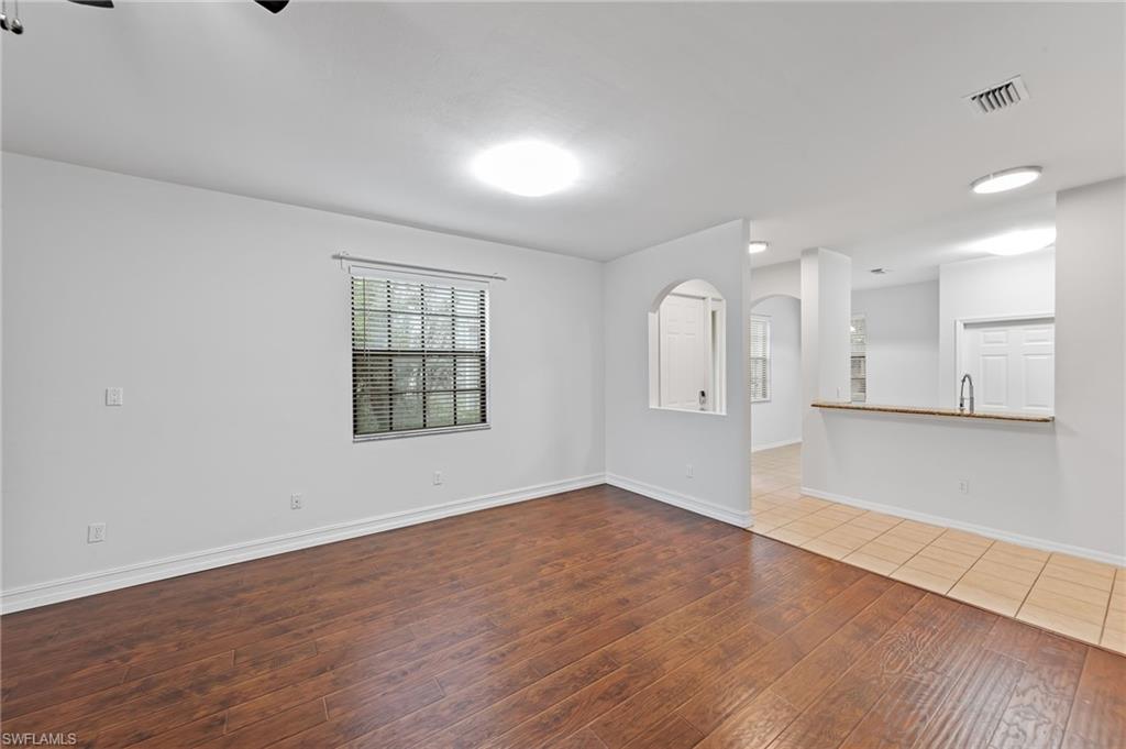 Unfurnished living room featuring dark wood-style floors, arched walkways, and a ceiling fan