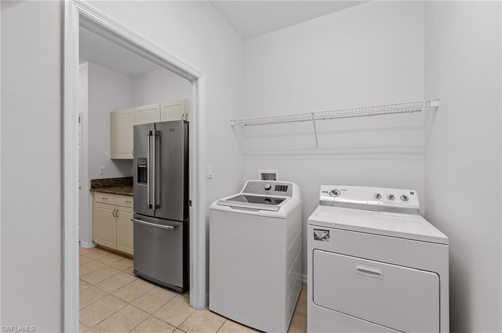 Washroom featuring washing machine and clothes dryer and light tile patterned floors