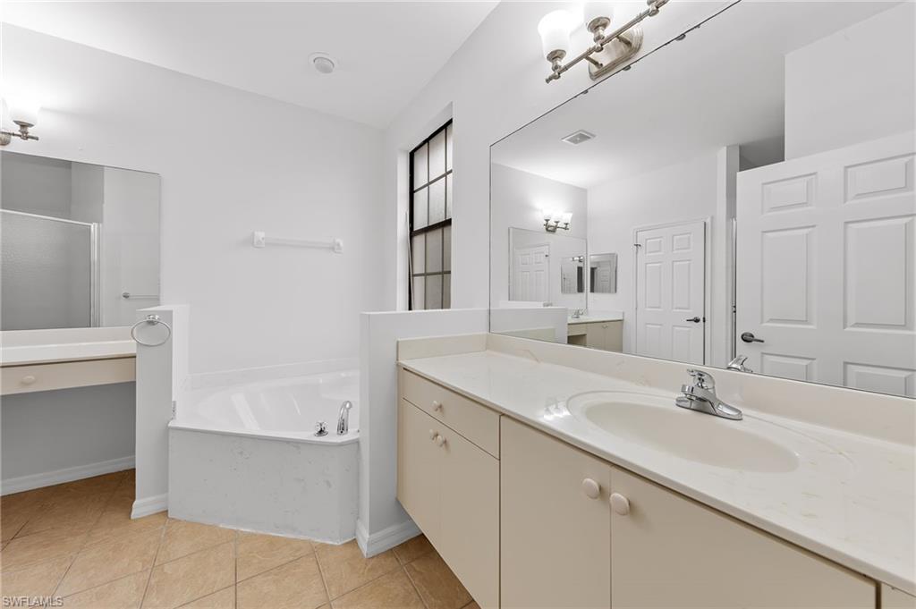 Full bathroom featuring vanity, a shower stall, light tile patterned floors, and a bath