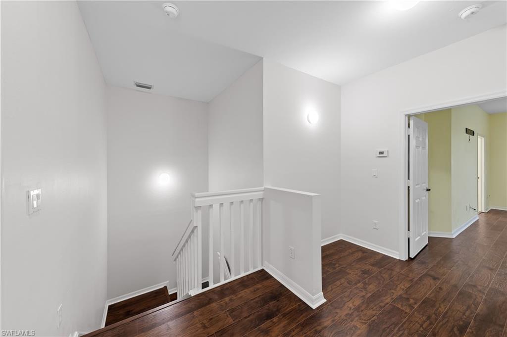 Corridor featuring an upstairs landing and dark wood-style floors