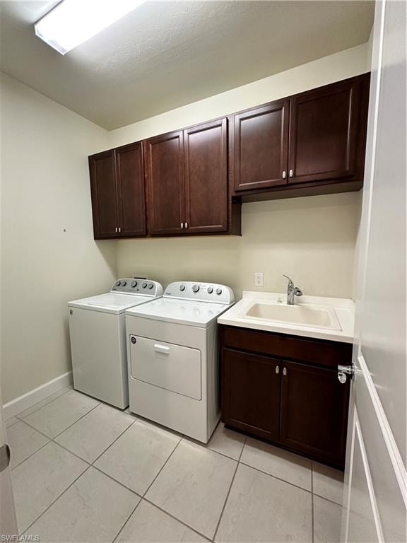 Laundry room featuring separate washer and dryer, cabinets, sink, and light tile patterned flooring