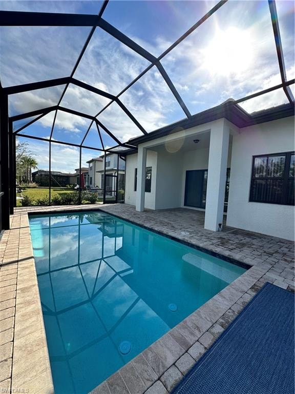 View of swimming pool featuring glass enclosure and a patio area