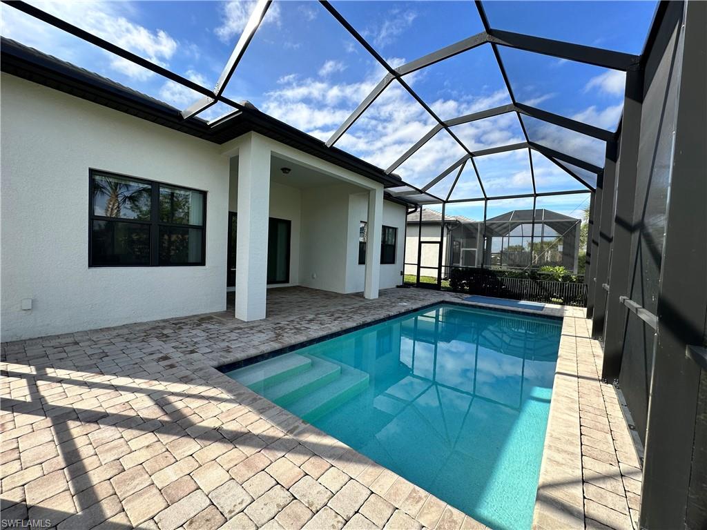 View of swimming pool featuring a patio and a lanai