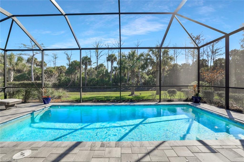 Screened-in pool area featuring an in-ground swimming pool with clear blue water
