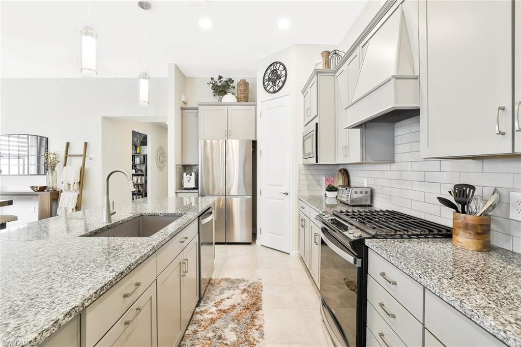 Modern kitchen featuring light gray cabinetry, stainless steel appliances, and granular countertops