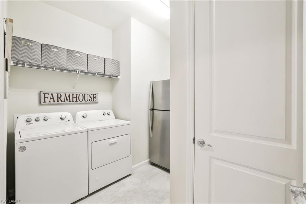 Dedicated laundry area featuring a washer and dryer set, wire shelving, and light-toned flooring