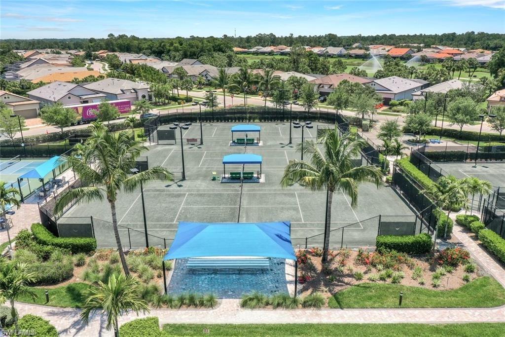 Multiple tennis courts featuring green playing surfaces, perimeter fencing, and overhead lighting