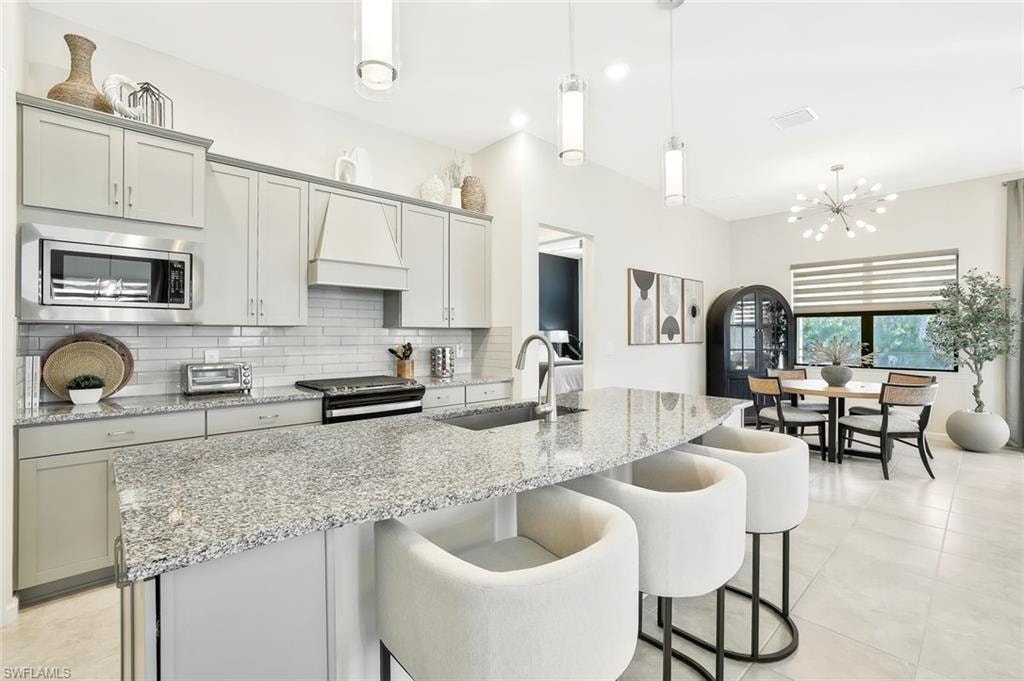 Modern kitchen with a spacious island featuring granite countertops, a stainless steel sink, and pendant lighting