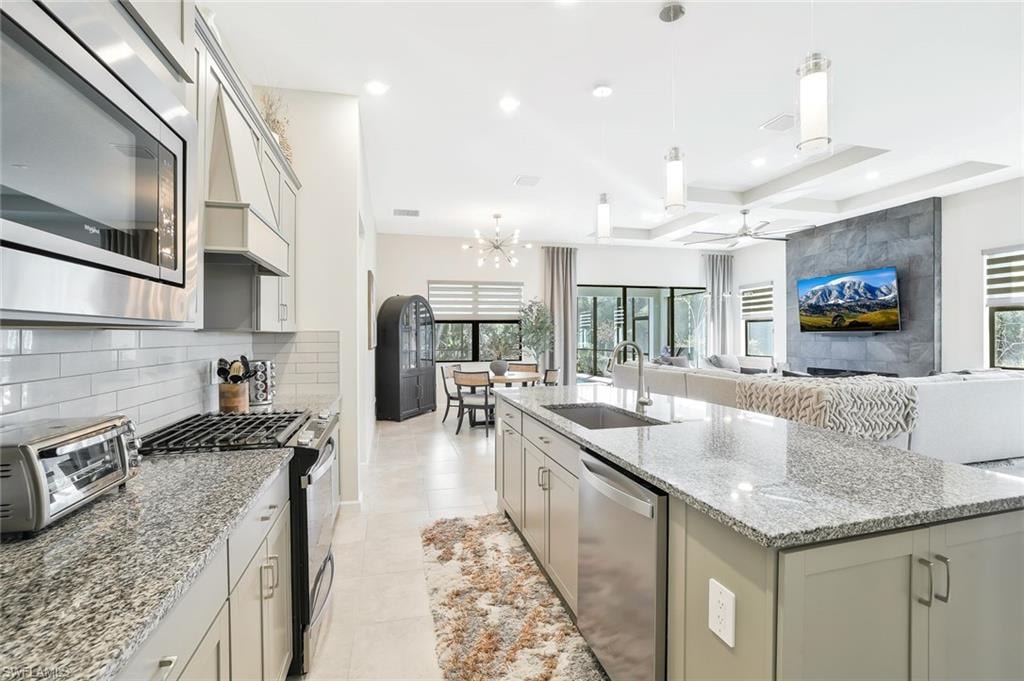 Well-appointed kitchen featuring granite countertops, stainless steel appliances, a subway tile backsplash, and light-toned cabinetry