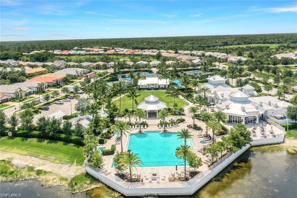 Expansive community recreation center featuring a large swimming pool, surrounding lounge areas, and multiple structures with white roofs