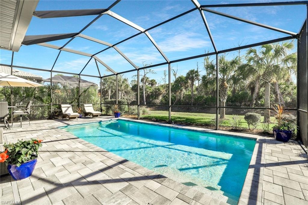 Screened swimming pool with a paved patio surround, featuring integrated steps and a clear blue water surface